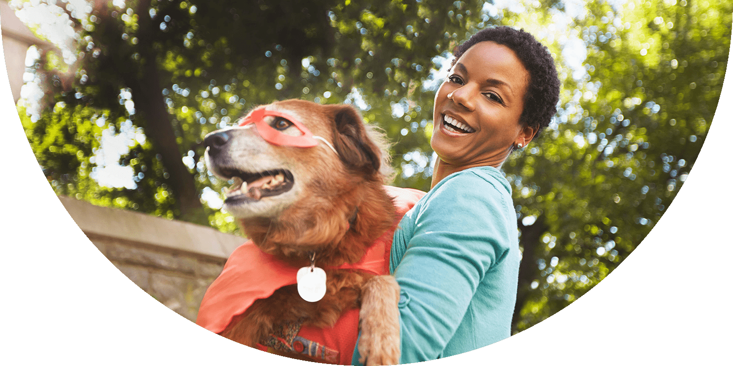 Laughing woman holding a dog in a superhero costume